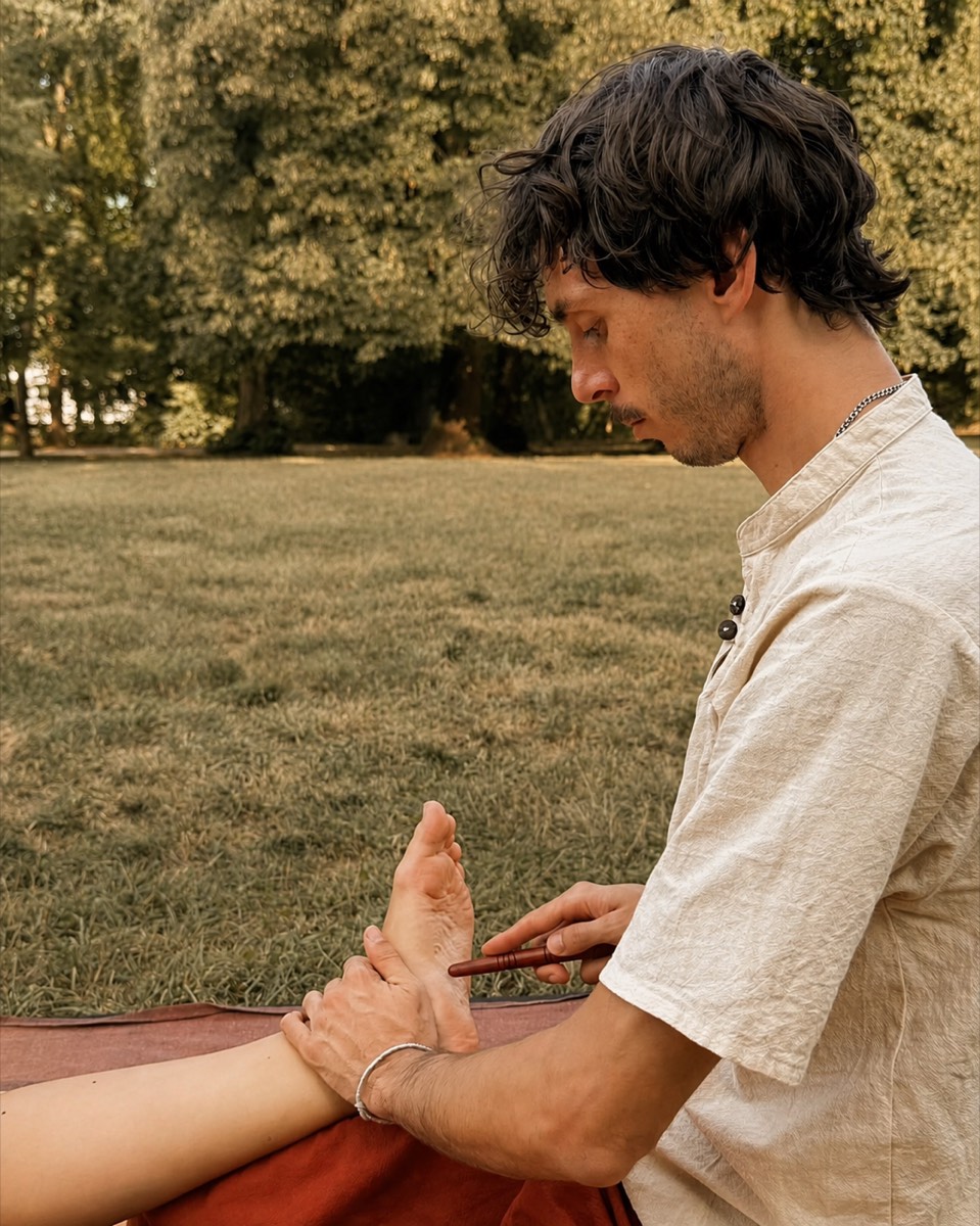 Roman giving a traditional Thai foot massage outdoors in a Munich park